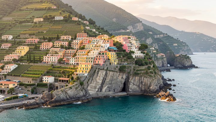 Vue panoramique des villages colorés des Cinque Terre surplombant la mer Ligurienne sous une lumière douce.